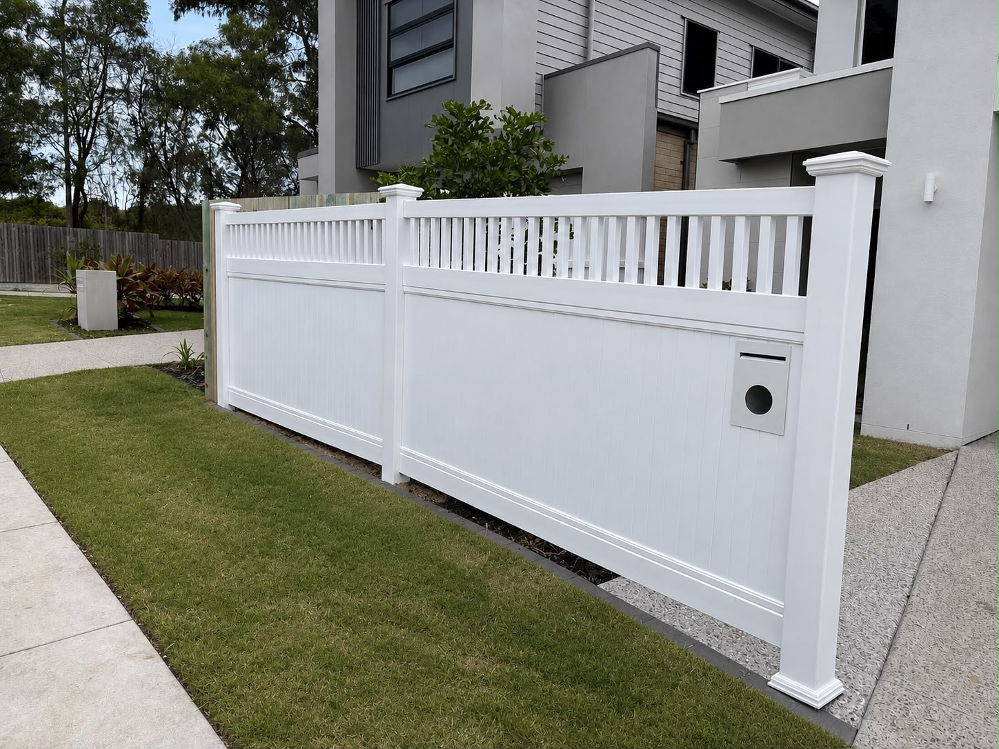 White PVC privacy fence with decorative vertical slats at a modern home