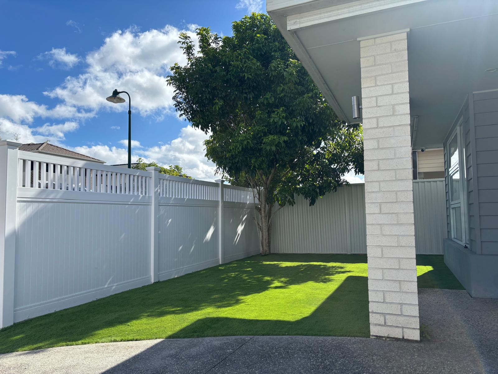 White PVC privacy fence around landscaped backyard